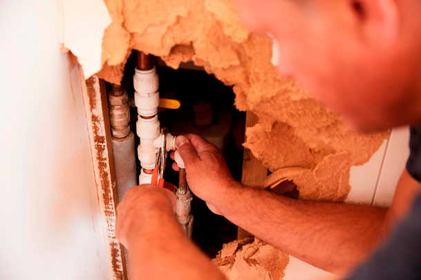 Rohrreiniger repariert ein undichtes Rohr hinter der Wand
