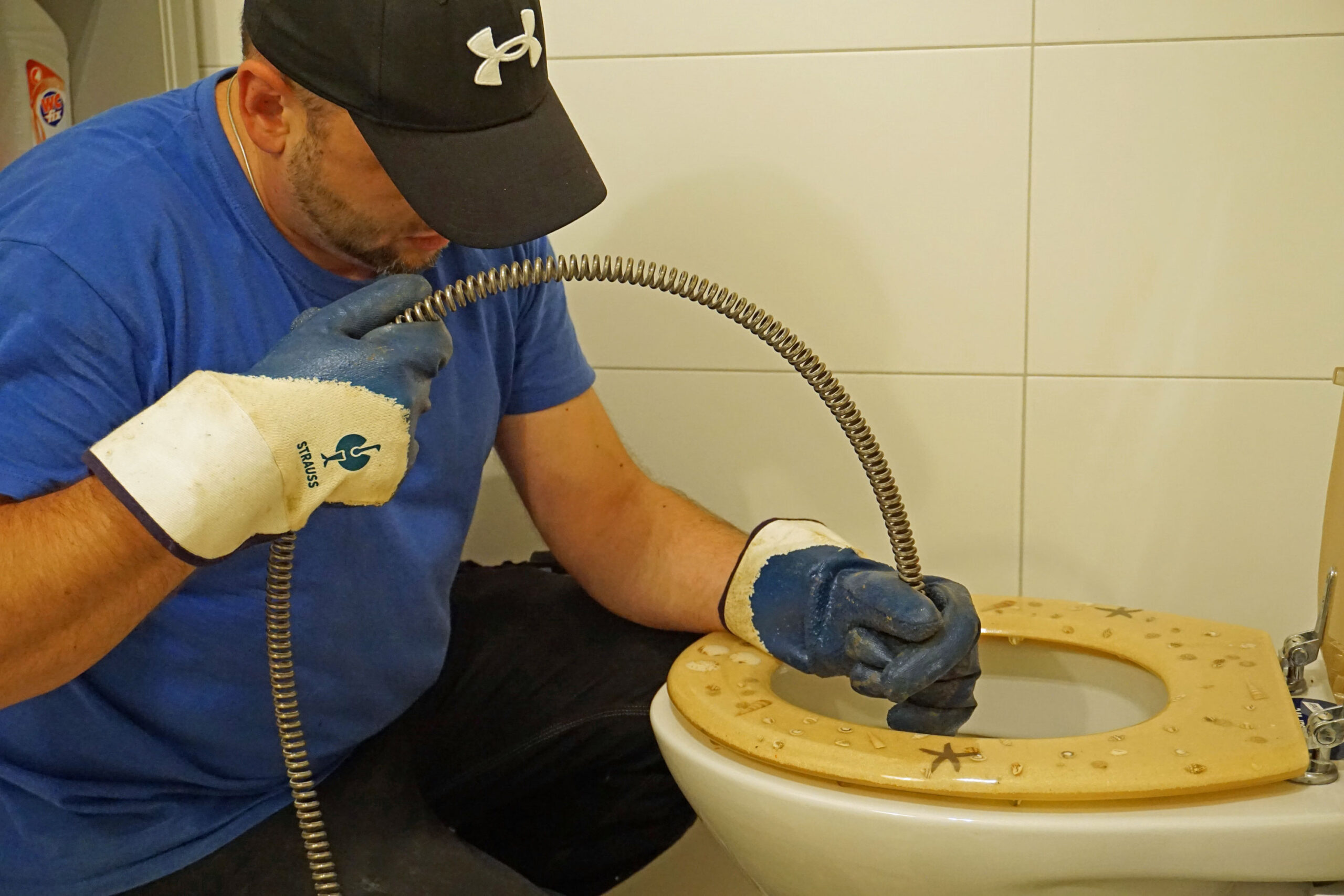 Unser Rohrreiniger beim Einführen einer elektrischen Spirale in ein verstopftes WC Unser Rohrreiniger beim Einführen einer elektrischen Spirale in ein verstopftes WC